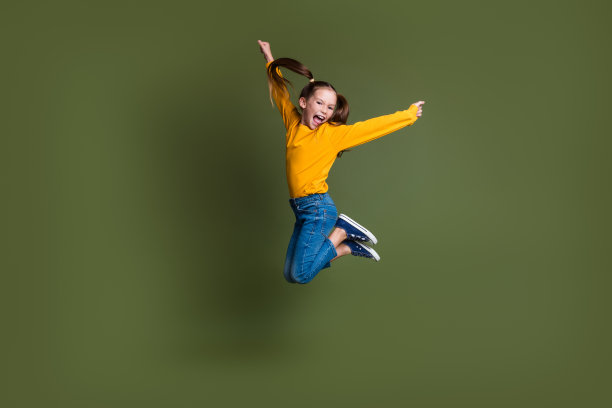 全身照片，疯狂的小孩扎着双马尾，穿着黄色毛衣，双手举起，尖叫，背景为卡其色。图片下载