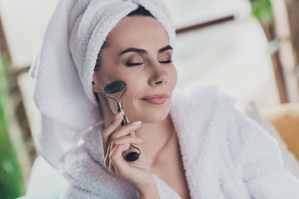 吸引人的女士在家中室内浴后使用面部按摩器的照片图片下载