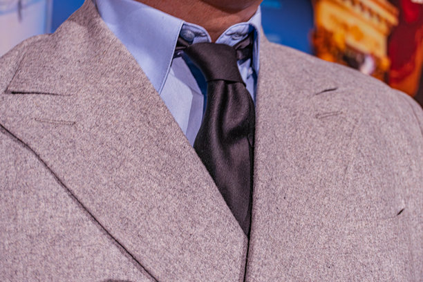 穿着轻便外套、深色图案衬衫、整齐打结的领带，可能佩戴头饰，室内环境，人工照明，没有其他物品或人物，可能是一张以时尚为主题的照片。图片下载