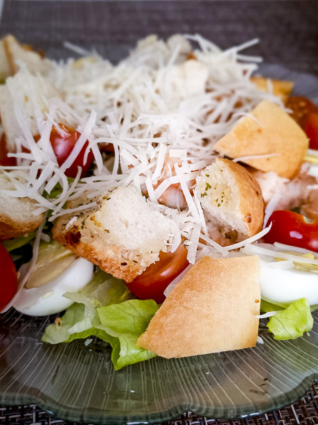 桌子上的盘子里盛着凯撒沙拉，配有面包丁和磨碎的帕尔马干酪。特写，竖版照片。图片下载