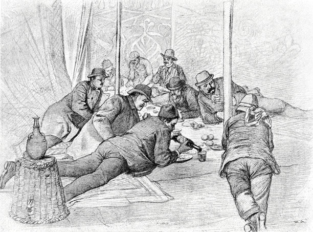 耶路撒冷的旅行者们在早餐帐篷里，男人们趴着或侧躺在一块大地毯上，面前摆满了食物，他们热烈地交谈着。图片下载