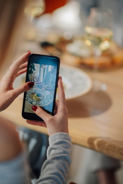 女性在餐厅用智能手机拍摄食物照片图片下载