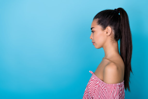 侧面照片，严肃自信的韩国女孩穿着红色上衣，凝视空旷的空间，适合品牌广告，背景为蓝色。图片下载