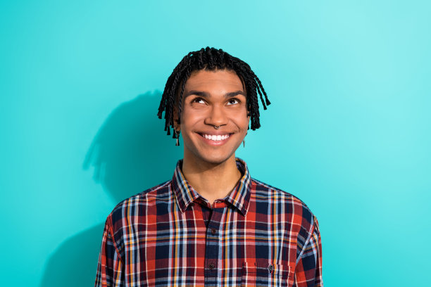 帅气年轻男子的照片肖像，仰望空旷的空间，穿着时尚的格子服装，背景为青色。图片下载