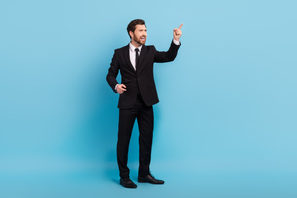 穿着黑色西装的愤怒老板在蓝色背景下尖叫并指向空旷的地方的全身照片图片下载