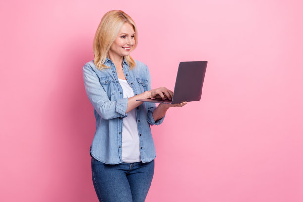 中年金发女教师在粉色背景下使用她的新苹果MacBook进行远程教育的照片图片下载