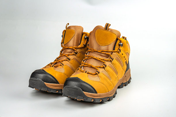 一张专注于坚固登山靴的图片，展示了可调节的合身性和对踝部的支撑，厚实的鞋底提供良好的抓地力。大地色调暗示了在各种地形上的耐用性，吸引冒险爱好者。图片下载