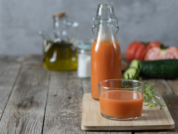 一张水平照片，展示了一杯冷汤和背景中的一瓶，放在托盘上，背景是木质的，周围有食材。留白空间。图片下载