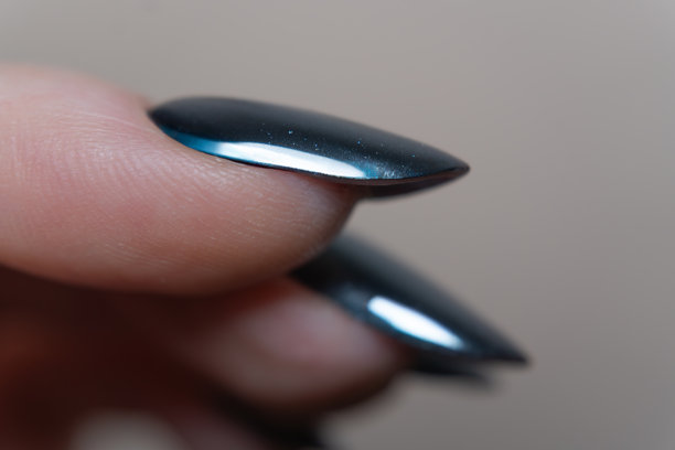 一张特写照片，展示了一根涂有黑色光泽的手指，指甲形状完美，指缘整齐——真正的修饰得体的手部典范。图片下载