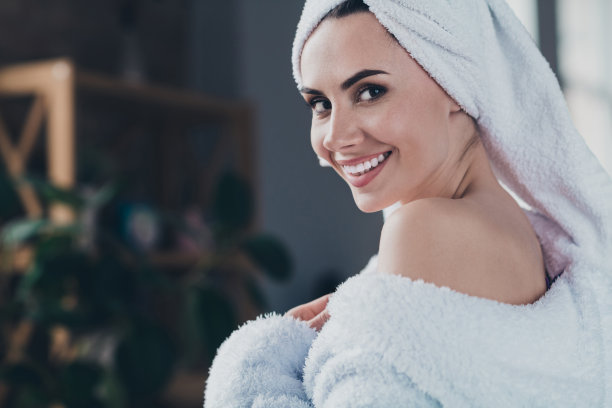 特写照片，快乐迷人的女士在家中穿着柔软的浴袍，享受水疗度假程序。图片下载