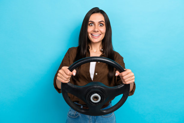 穿着棕色衬衫的快乐兴奋女士在蓝色背景下驾驶汽车的照片图片下载