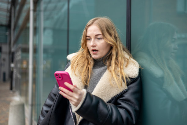 悲伤的30多岁女性在户外绝望地盯着智能手机屏幕。年轻女性在手机上收到坏消息。高质量照片。图片下载