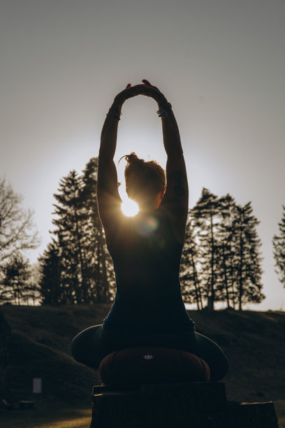 身材健美、快乐的年轻女性穿着运动服，在阳光明媚的早晨的自然公园中进行冥想、瑜伽、呼吸和拉伸练习。真实自然的照片。图片下载