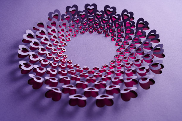 浪漫的圆形剪纸艺术作品，紫色背景上层叠的心形，情人节主题的静物画图片下载