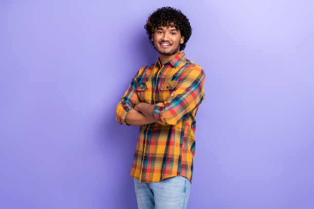 年轻快乐的阿拉伯印度裔男性首席执行官，卷发，双手交叉，独立于紫色背景的主办公室Facebook员工照片图片下载