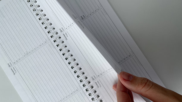特写镜头展示一只手翻动空白的螺旋计划本，完美体现组织、规划和生产力的概念。这张干净现代的图片非常适合商业、教育和时间管理项目。图片下载