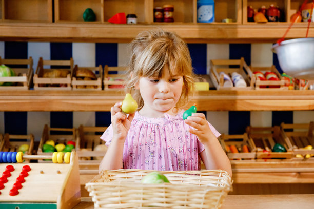小女孩在玩食物和杂货的木制玩具。快乐活泼的孩子在扮演收银员或卖家的角色，像是在木工店或超市里。适合儿童的教育活动。图片下载