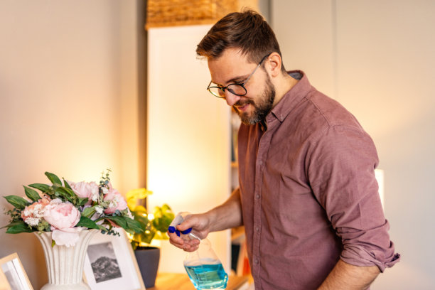 一个男人在家里清洁桌子，擦拭表面以保持空间的整洁和有序。这张图片捕捉了一个温馨日常环境中家庭维护和关注清洁的瞬间。图片下载