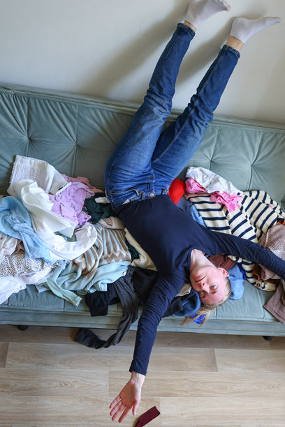 快乐的女性在一堆衣物中玩耍，温馨而自发的室内场景。高质量照片图片下载