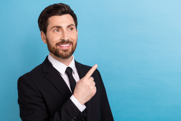 年轻男士穿着黑色时尚礼服，手指指向镜头，展现新颖保险的市场公司首席执行官照片，背景为蓝色。图片下载