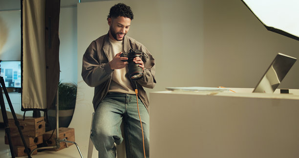 男子在摄影棚检查相机，查看拍摄结果、目录和选择。微笑的人与技术，镜头对焦，电影制作和编辑照片，服务于摄影行业。图片下载