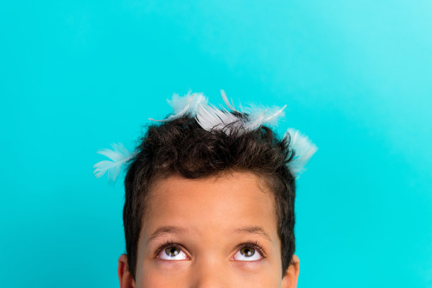 特写裁剪照片，学校孩子的羽毛头，目光好奇地望向空旷的空间，背景为青色。图片下载