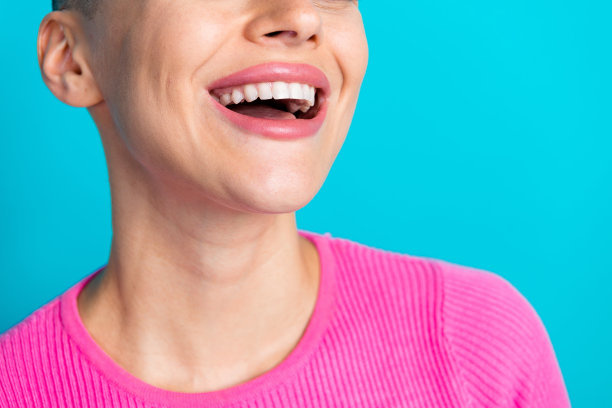 漂亮年轻女孩的照片肖像，笑容灿烂，洁白健康的牙齿，穿着时尚的粉色服装，背景为水绿色。图片下载