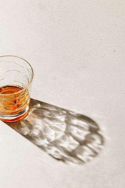 阳光下的透明酒杯投影，放在米色混凝土桌面上，俯视角度，极简风格，审美照片，闪亮的玻璃在自然光下闪烁，夏季烈酒，静物摄影图片下载