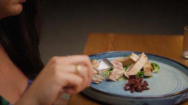 女人用叉子切割金枪鱼的晚餐片段图片下载