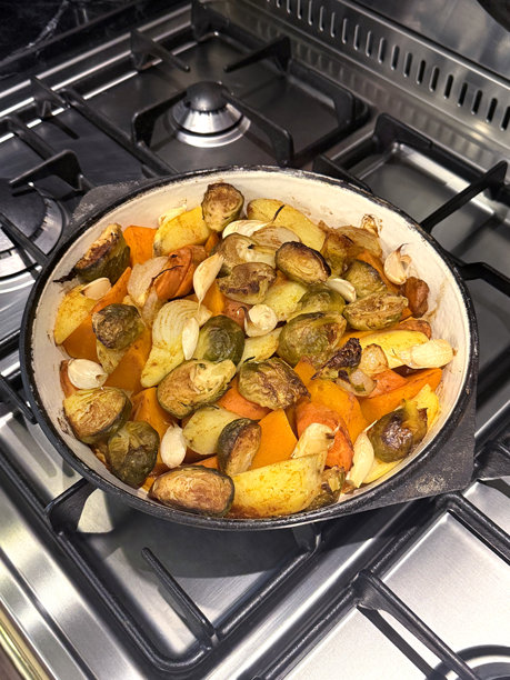 烤蔬菜：土豆、南瓜、胡萝卜、大蒜和球芽甘蓝在铸铁煎锅中。基于蔬菜的自制食品概念。手工拍摄的手机照片，选择性对焦，非人工智能。图片下载