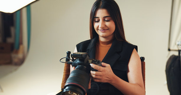 微笑的女性与摄影师检查相机以查看拍摄结果、目录和选择。人物、技术和镜头聚焦于拍摄制作、编辑图片和摄影行业的幕后。图片下载