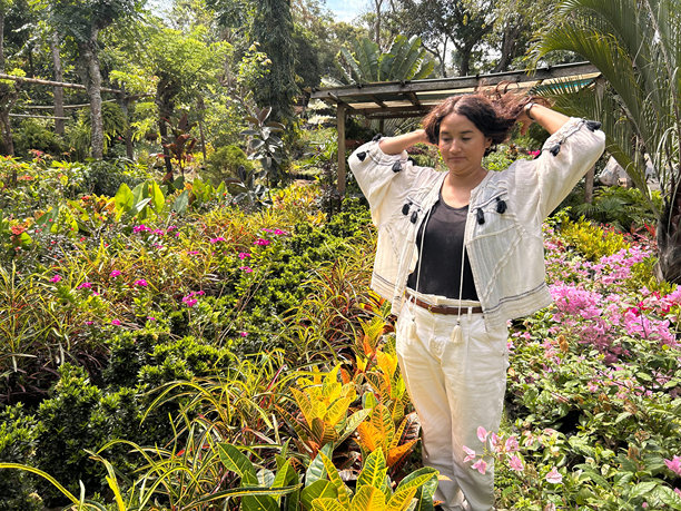 一位女性在植物和花卉苗圃中触摸自己的头发的照片图片下载