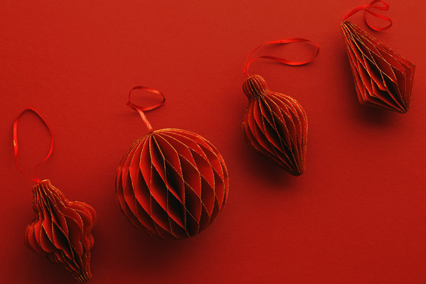 节日红色纸质圣诞装饰品，悬挂的红色手电筒或灯笼排成一行，蜂窝状斯堪的纳维亚风格装饰在红色背景上，简约单色照片，节日假日俯视图，留白空间图片下载