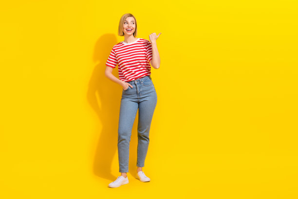 穿着T恤、手插口袋的惊讶女孩，直视着明亮黄色背景上空荡荡的折扣空间的全身照片。图片下载