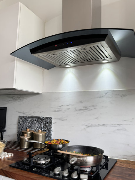 现代厨房的图片，配有燃气灶和煎锅/烹饪灶台，下面是时尚的抽油烟机烟囱。图片下载