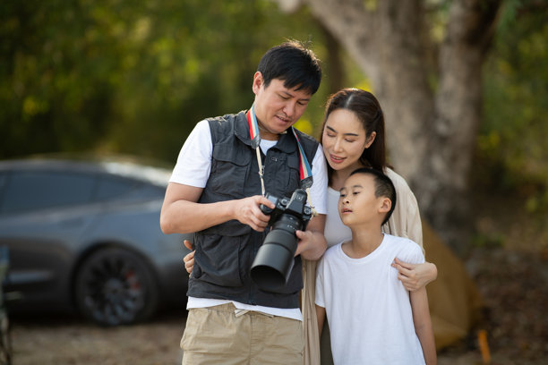 父亲正在向母亲和儿子展示他在相机上拍摄的照片。家庭旅行，去露营。图片下载