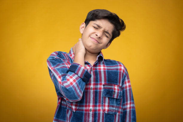 穿着格子衬衫的年轻男孩，背景为黄色，库存照片图片下载
