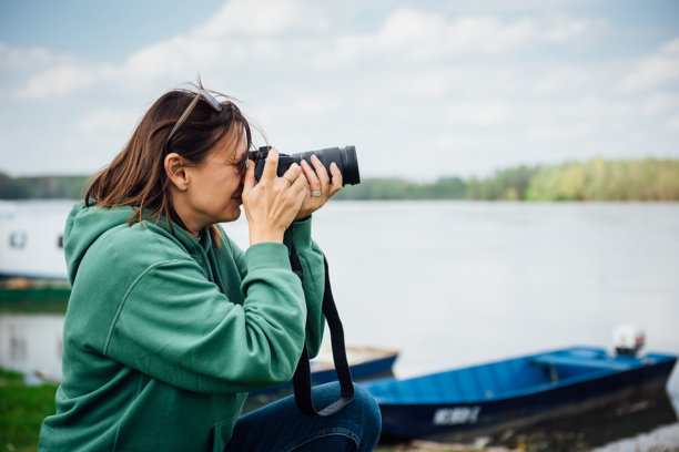 一位年轻女性旅行者用单反相机拍摄周围自然风光的照片图片下载