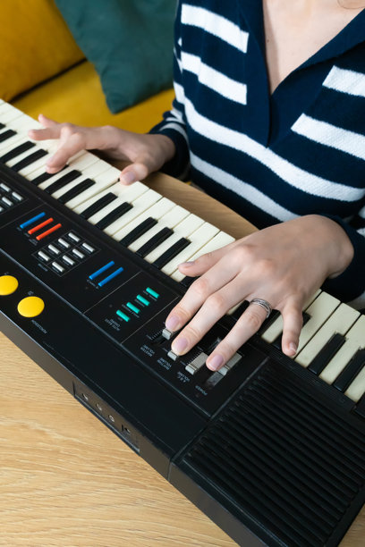 女性音乐家在温馨的家居环境中使用复古合成器键盘创作电子音乐，唤起怀旧情感和对复古音色的热爱。竖版照片图片下载
