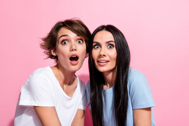 疯狂年轻女孩的照片肖像，棕色头发，张嘴惊讶地看着你，购物狂，背景为粉色。图片下载