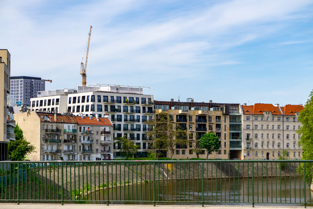 弗罗茨瓦夫奥德河沿岸的开发景观。这张照片展示了弗罗茨瓦夫奥德河堤的全景。前景中有一座带绿色栏杆的桥，桥后是各种建筑开发。图片下载