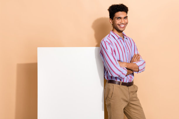 年轻帅气男性的照片肖像，双臂交叉，穿着时尚的条纹正装，背景为米色海报。图片下载