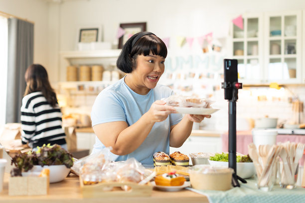 小企业主正在销售。亚洲糕点店老板喜欢在社交媒体上发布她的蛋糕照片和评论，或通过在线营销直播来宣传小企业，利用社交媒体的力量和在线营销来赚取更多收入。图片下载