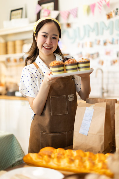 小企业主正在销售。亚洲糕点店老板喜欢在社交媒体上发布她的蛋糕照片和评论，或通过在线营销直播来宣传小企业，利用社交媒体的力量和在线营销来赚取更多收入。图片下载