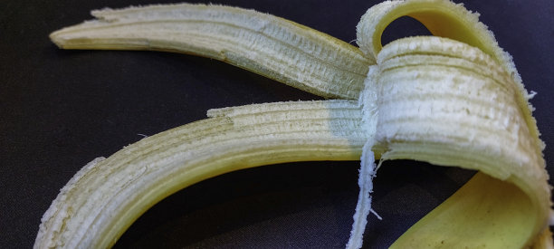 早餐照片，甜美成熟的剥皮香蕉，作为健康的选择。剥皮香蕉与黑色背景。图片下载