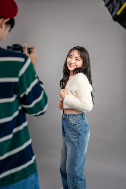 亚洲美丽女性模特与摄影师在摄影工作室工作。吸引人的专业摄影师为年轻女孩拍摄美丽的照片，背景用于制作广告图像。图片下载