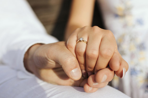 一对情侣手牵手的订婚照片，重点展示订婚戒指。图片下载