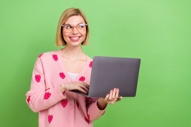 漂亮年轻女孩的照片肖像，穿着时尚的粉色草莓印花服装，坐在空旷的地方，背景为绿色。图片下载