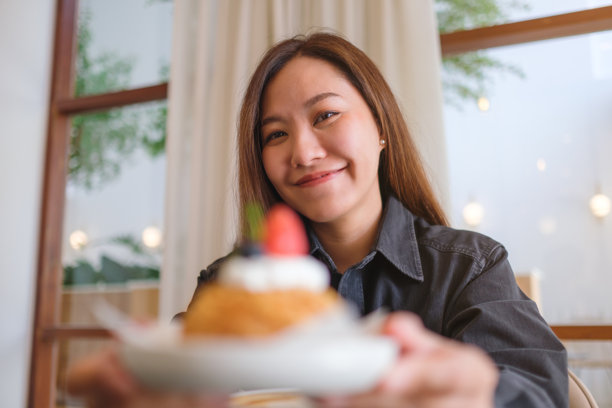 一位女性在咖啡馆里端着草莓泡芙奶油的肖像照片图片下载