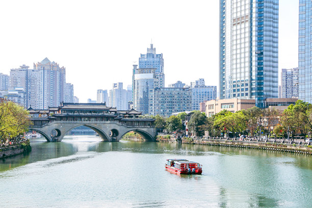 锦江河上游船即将穿过标志性的古老安顺桥，背景是现代建筑的风景照片图片下载